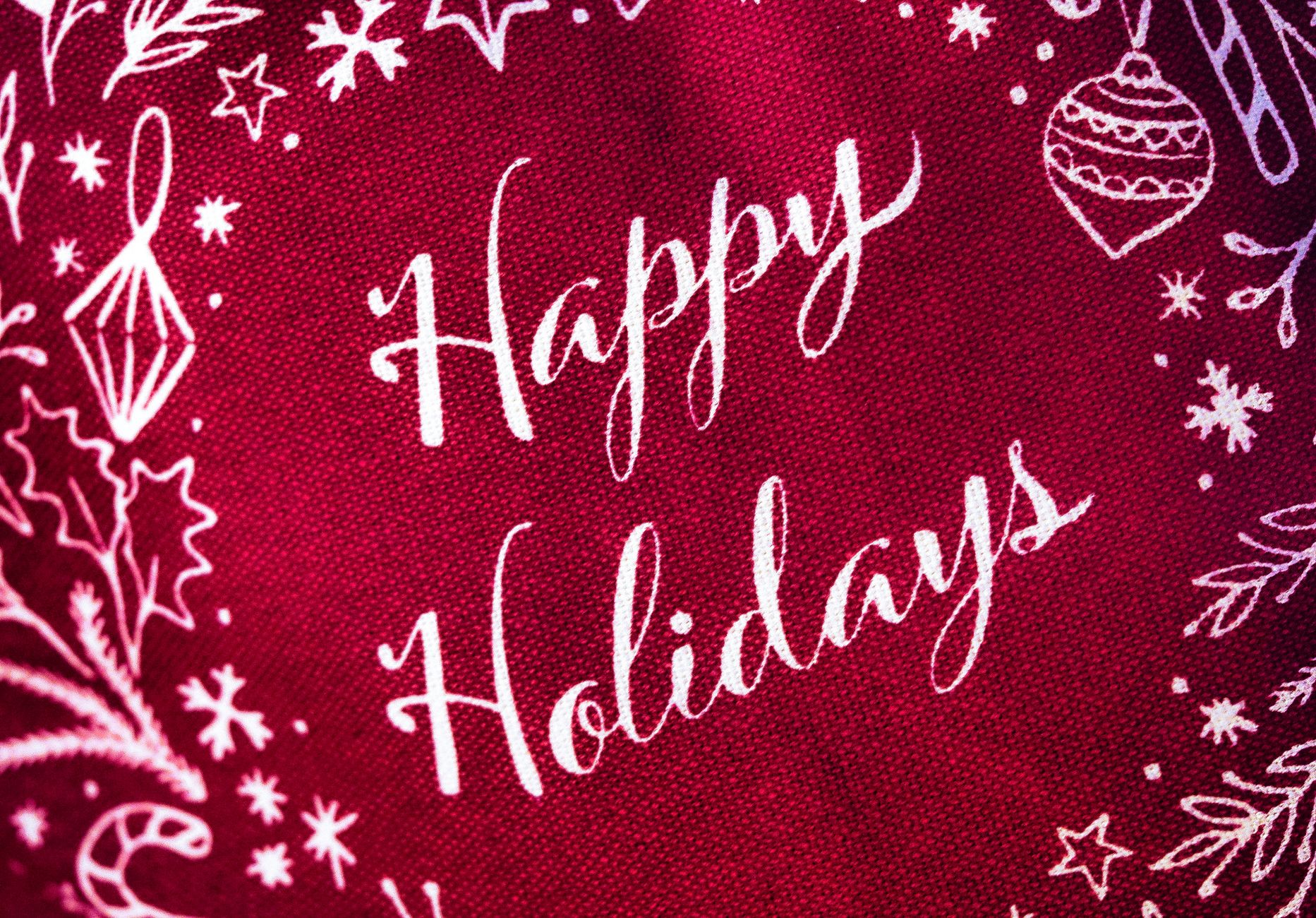 Bright red fabric with white 'Happy Holidays' and festive decorations for a cheerful holiday vibe.
